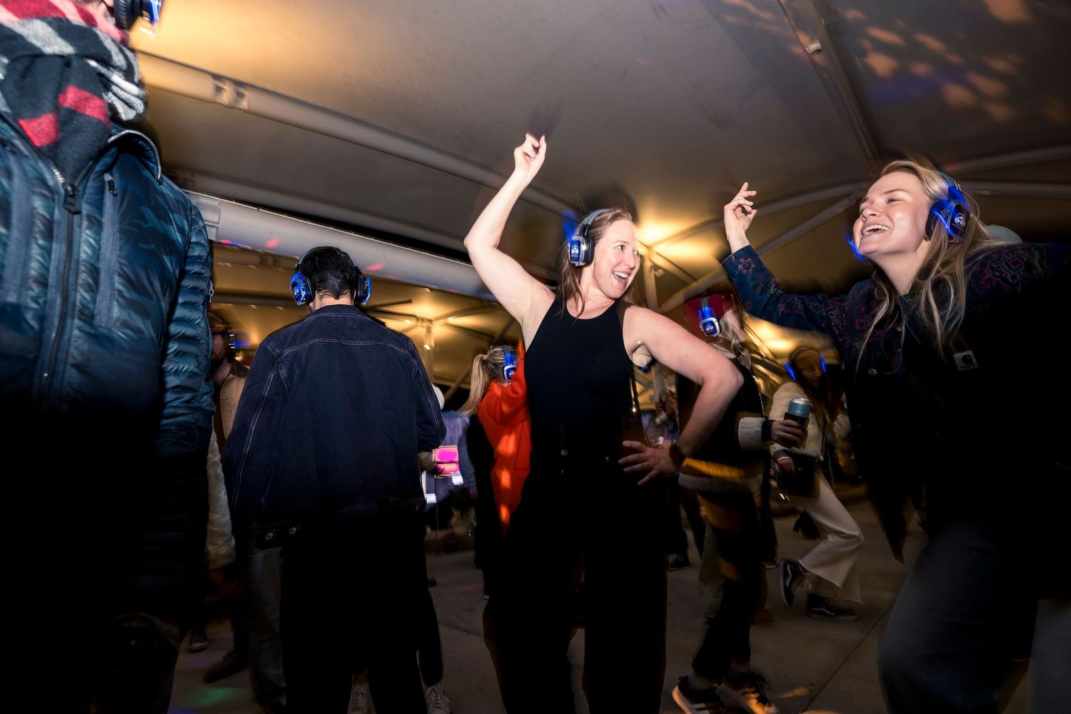 Dance floor filled with energetic people moving and celebrating at a dimly lit party venue.