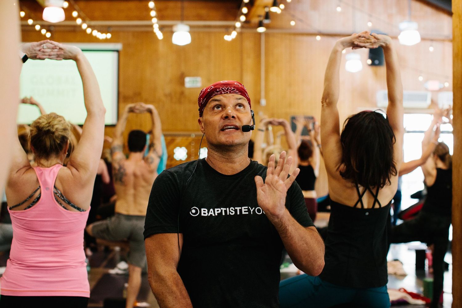 Fitness participants move rhythmically during an energetic exercise class in a wood-paneled studio.