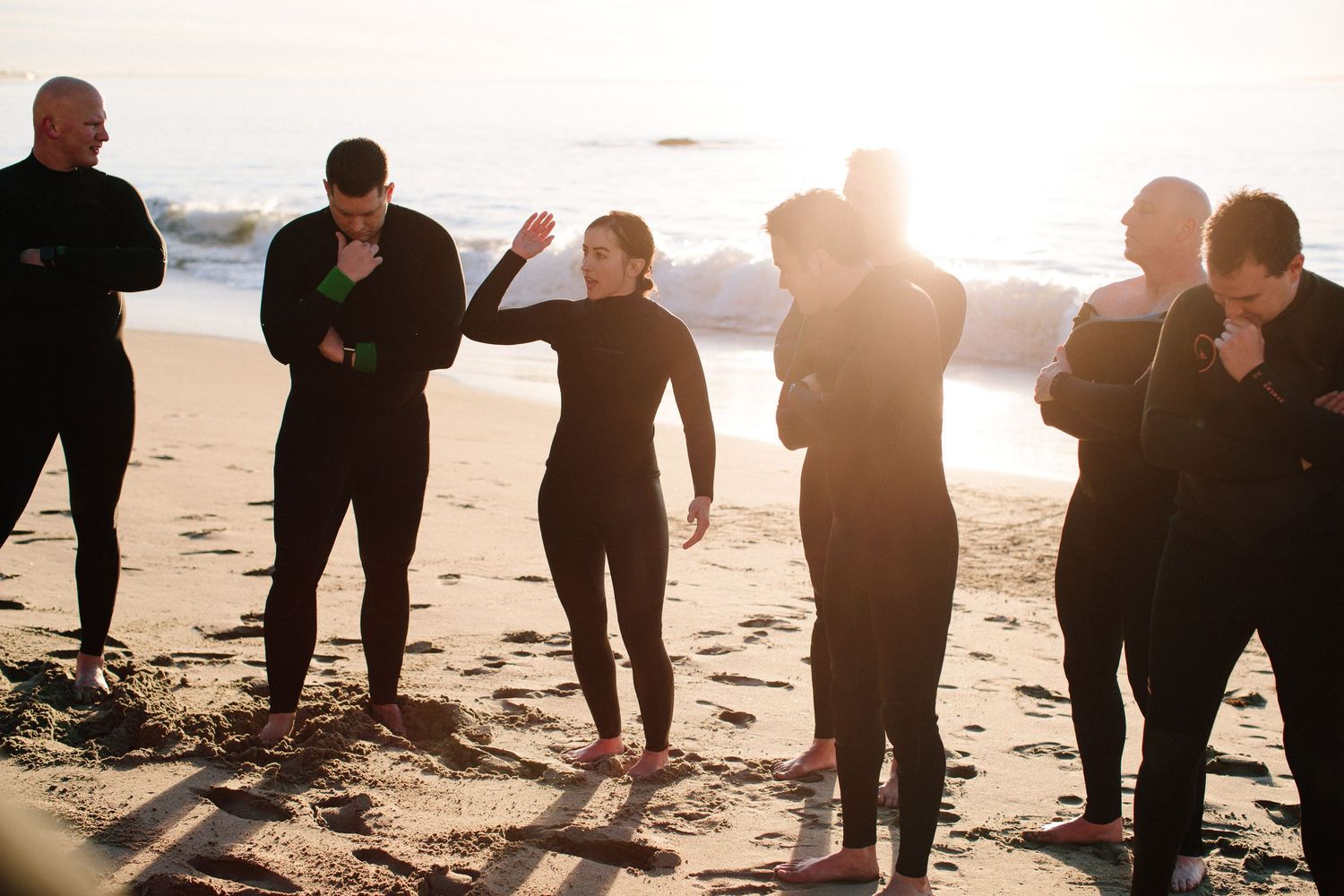 Silhouettes of a group sitting and interacting on a beach during golden hour.