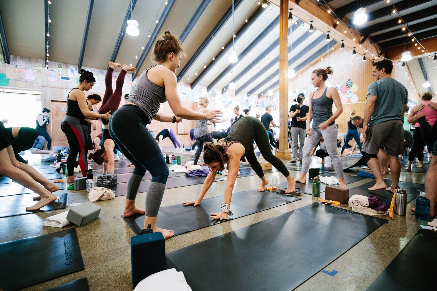 Yoga practitioners stretching and moving through poses on mats in a bright studio space.