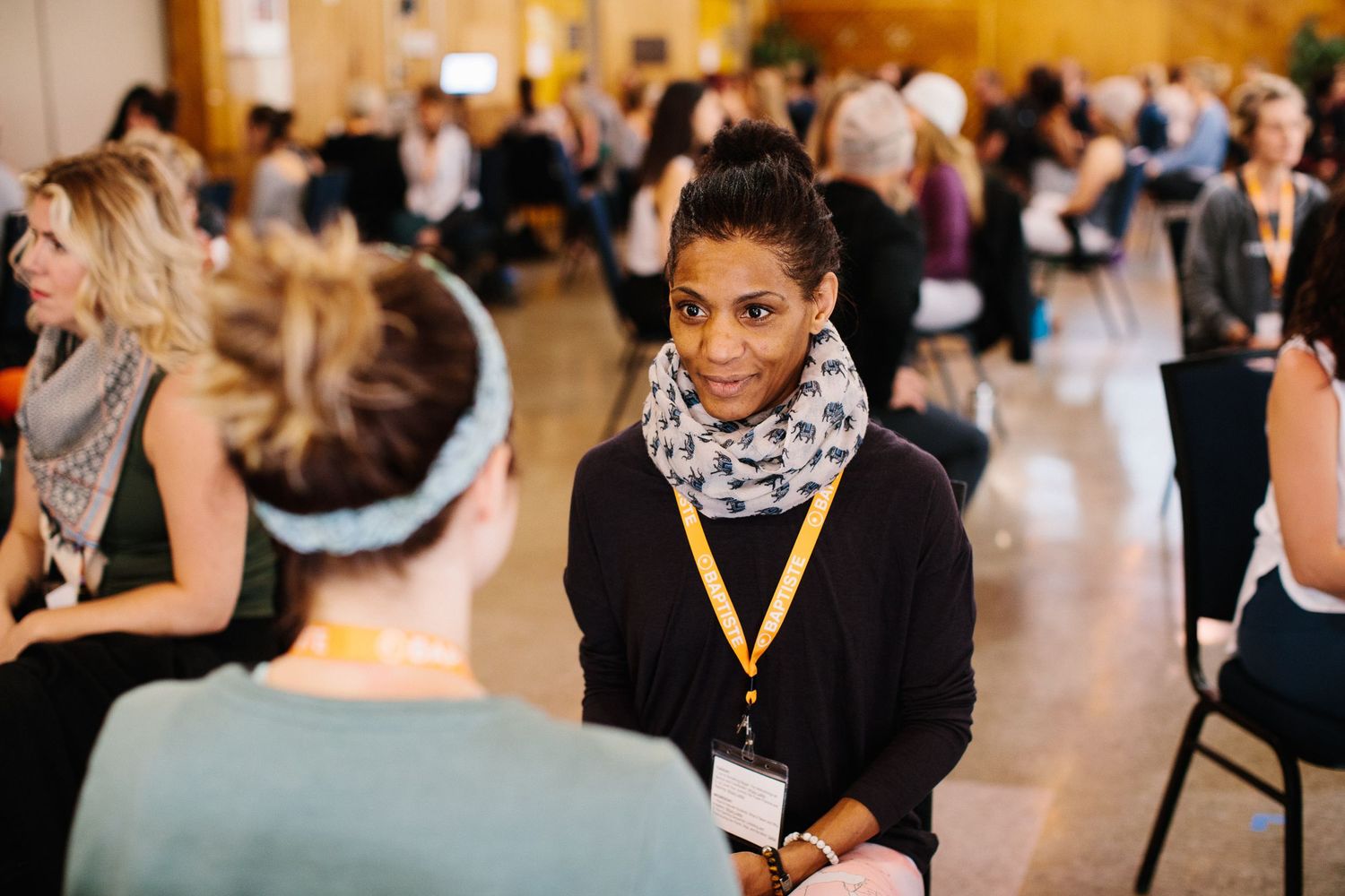 Conference attendee in professional attire seated during indoor event.