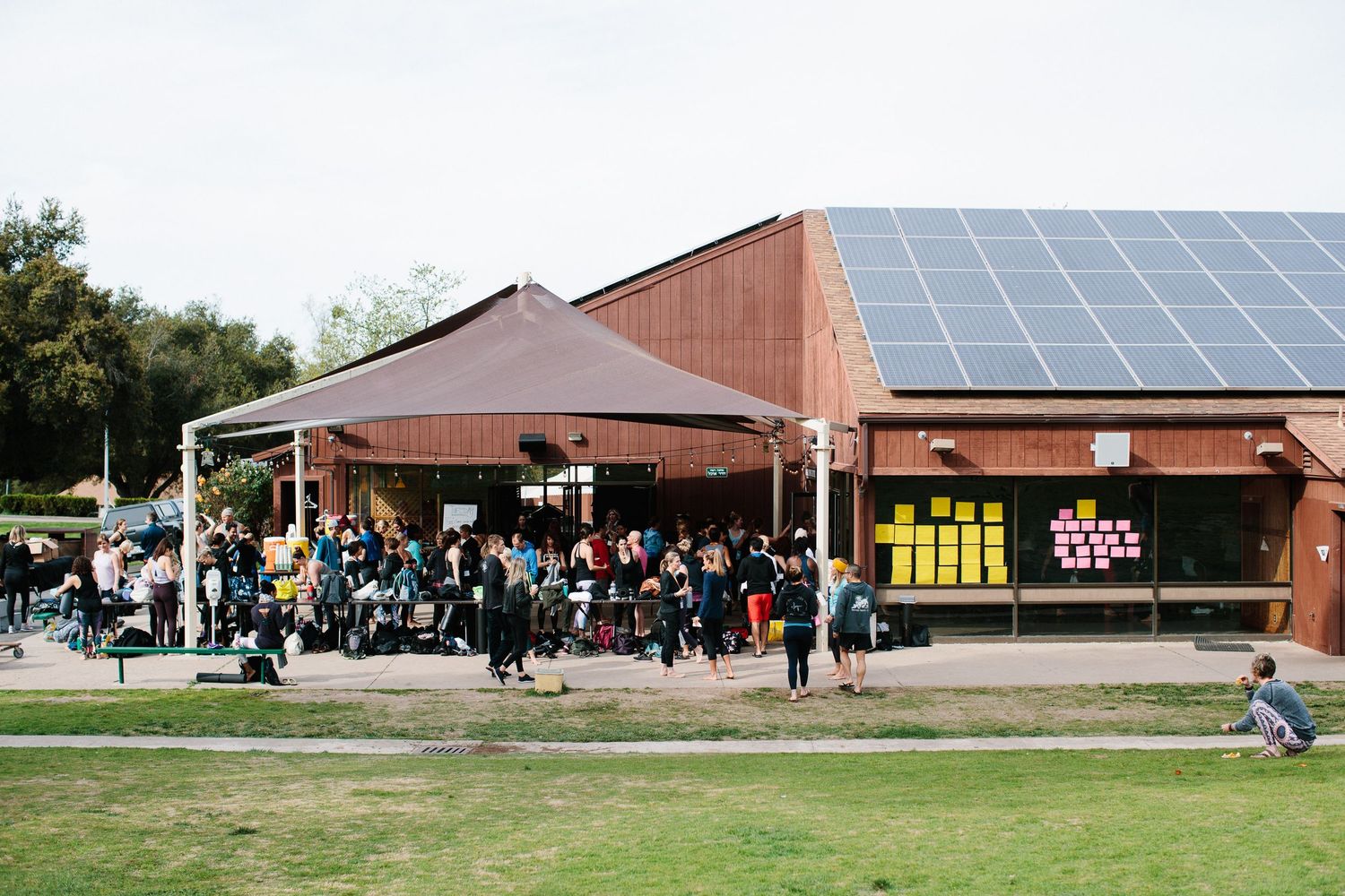 People gathering outside a brick building with solar panels and event signage.