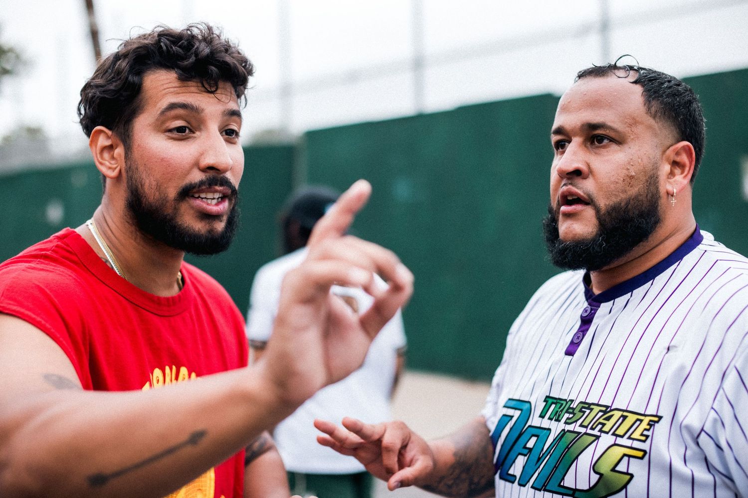 Two baseball players engaged in animated discussion while standing on outdoor field.