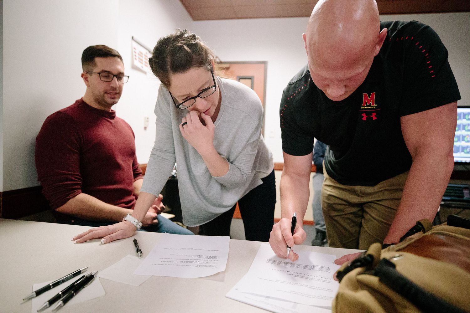People reviewing and signing documents together at a table during a meeting.