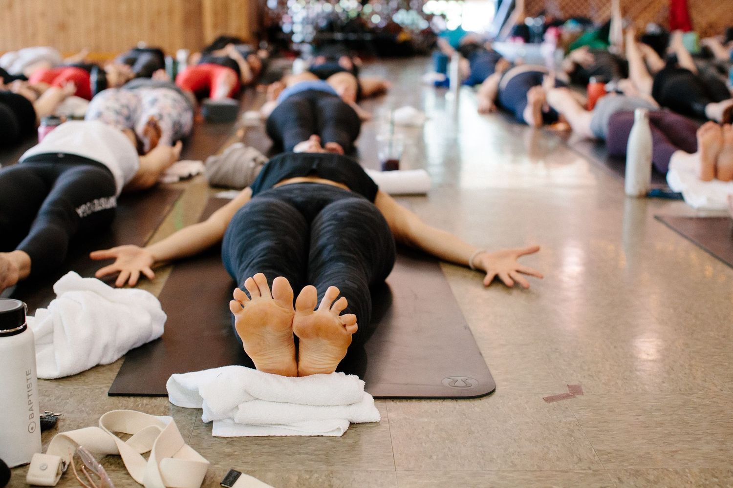 Group yoga class participants relaxing in savasana pose on exercise mats.