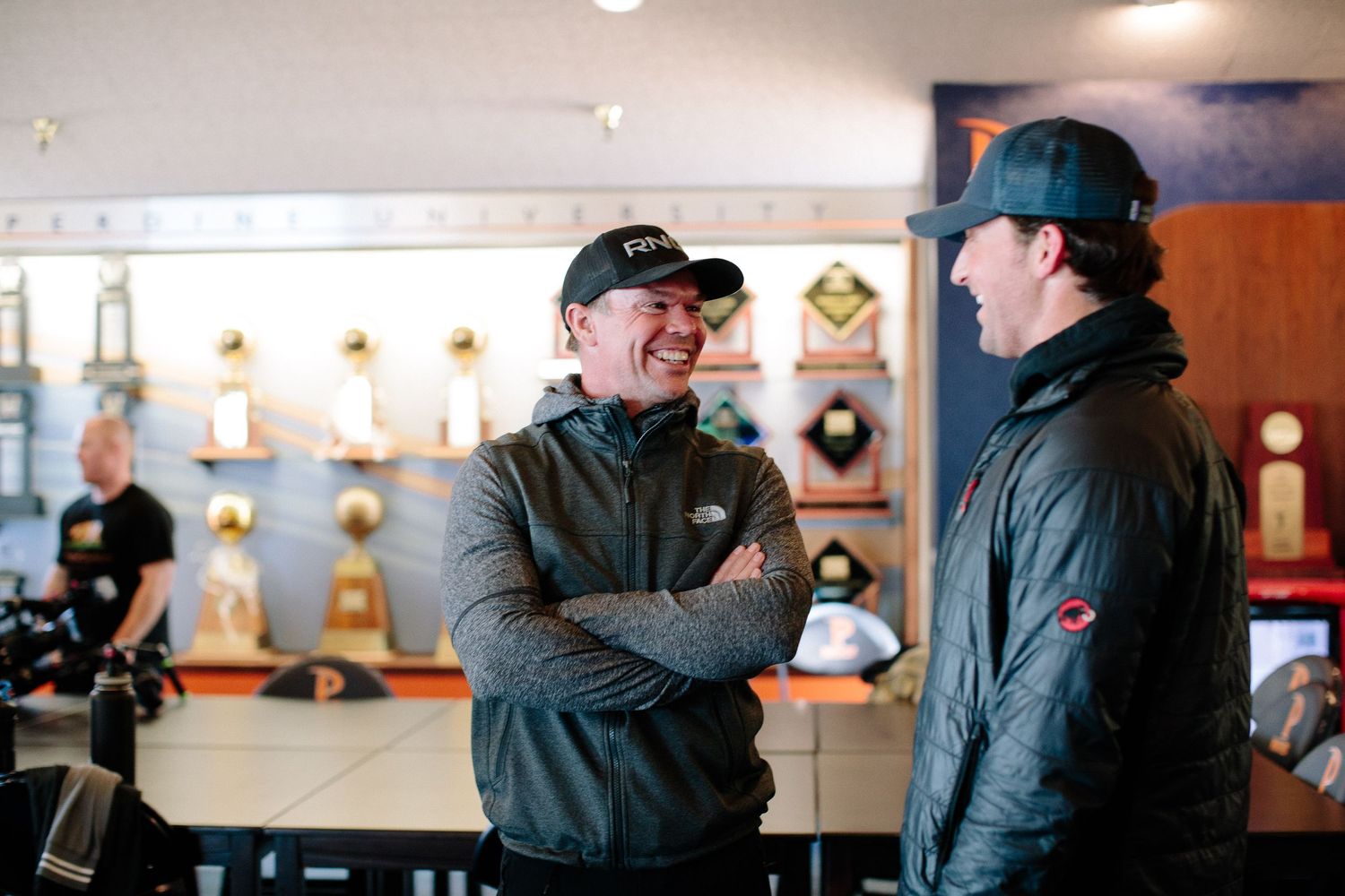 Candid interactions between two people wearing dark coats in an indoor setting.