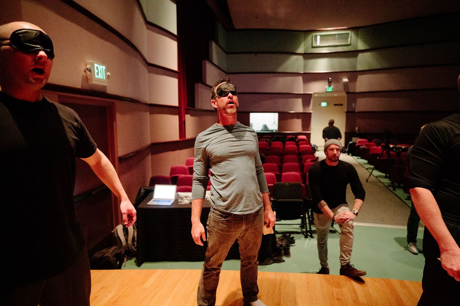 People practicing movements in a dimly lit studio space.
