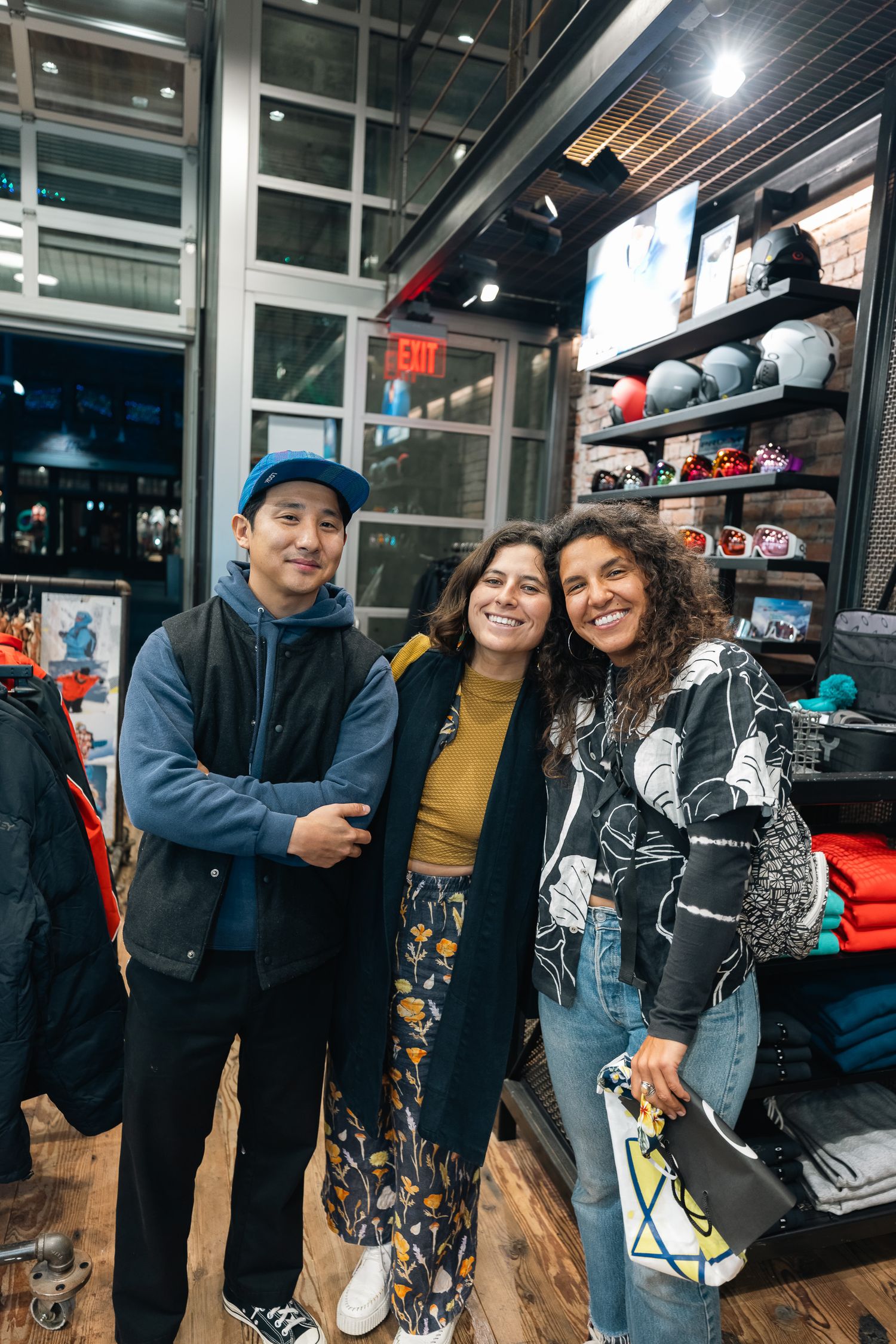 Three people posing together in a retail store with merchandise displays in the background.