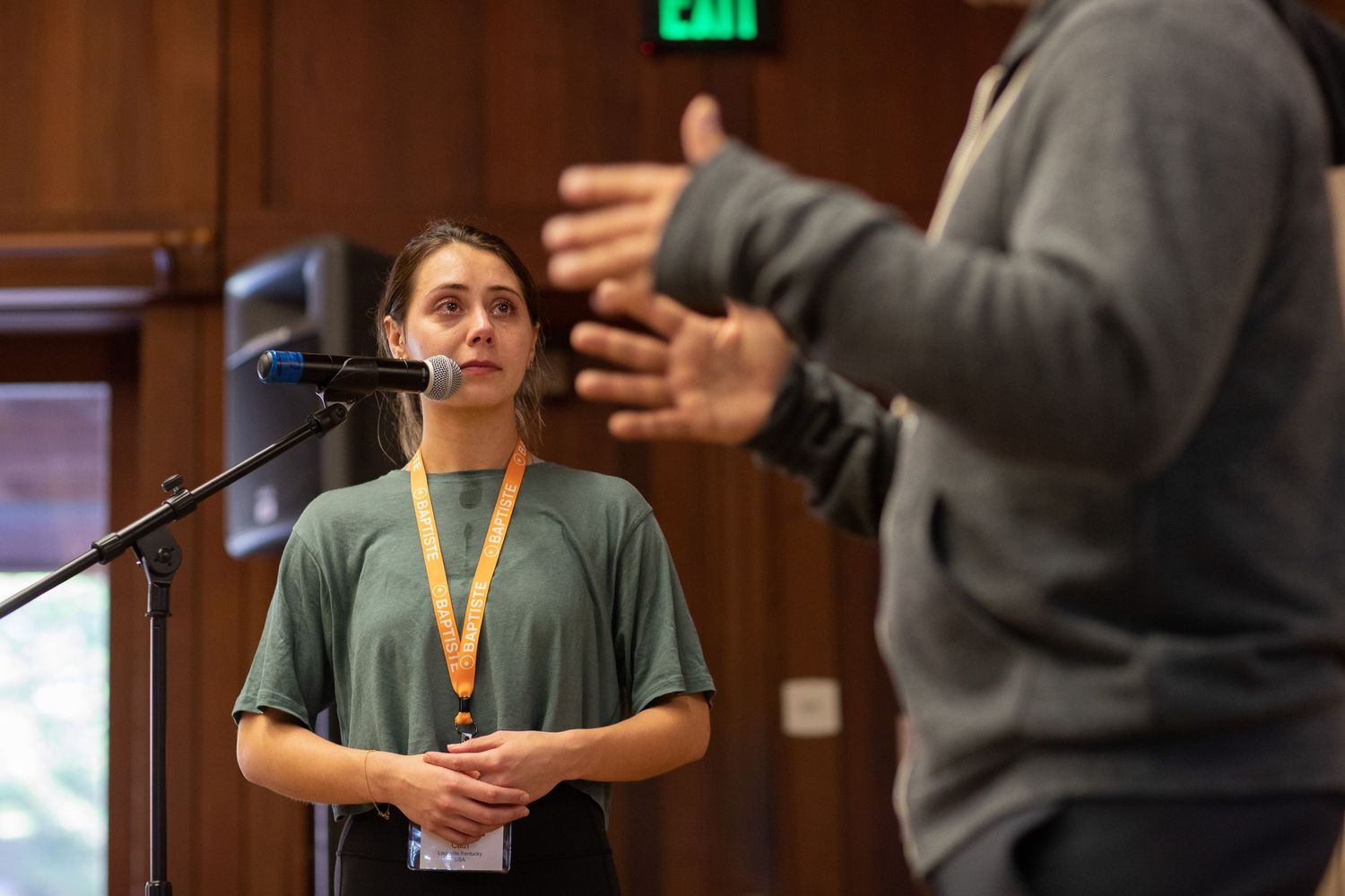 Speakers and attendees interact during a conference breakout session in a wood-paneled room.