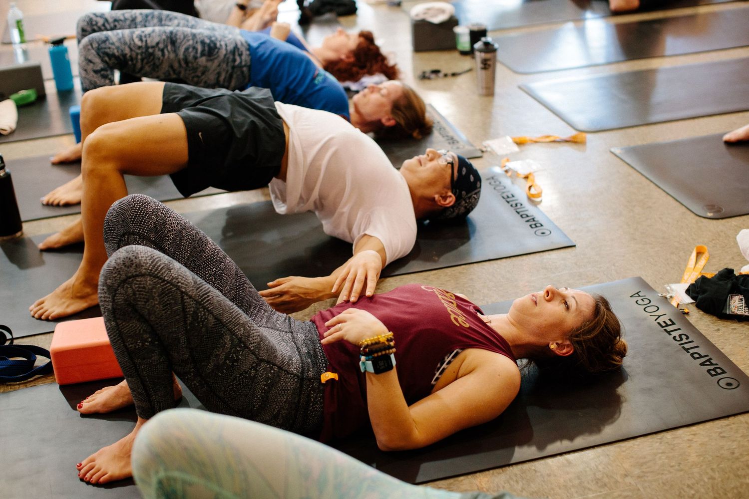Students lying on yoga mats during relaxation pose in a group fitness class.