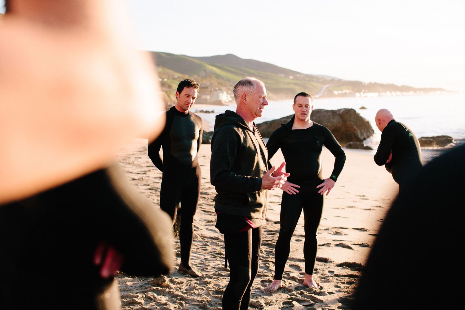 Group gathers on a scenic beach during an outdoor wellness activity.