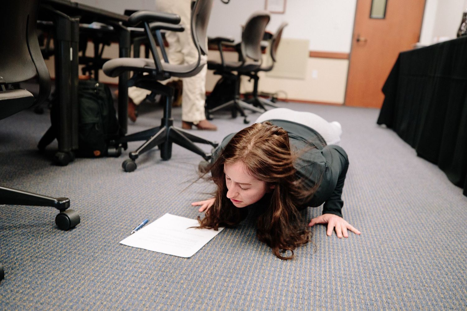 People working in an office space with gray carpet and multiple workstations.