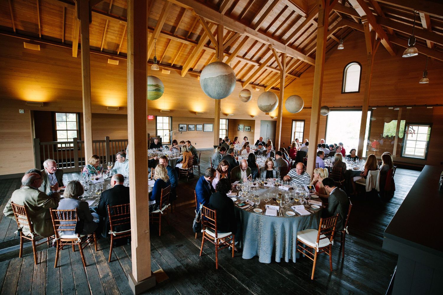 A rustic wedding reception venue with wooden beams and blue paper lanterns hanging from the ceiling.