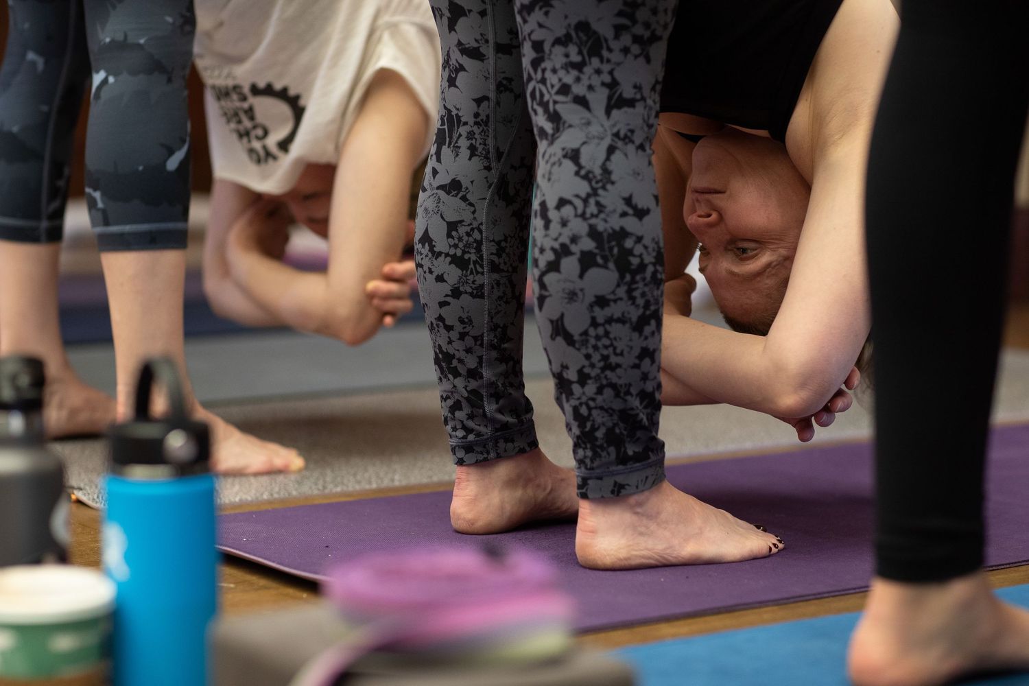 Close-up of feet and yoga mats during a fitness class with water bottles visible.
