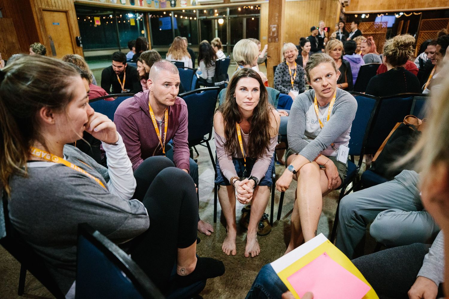 People sit in chairs arranged in a circle during a group discussion session in a community space.