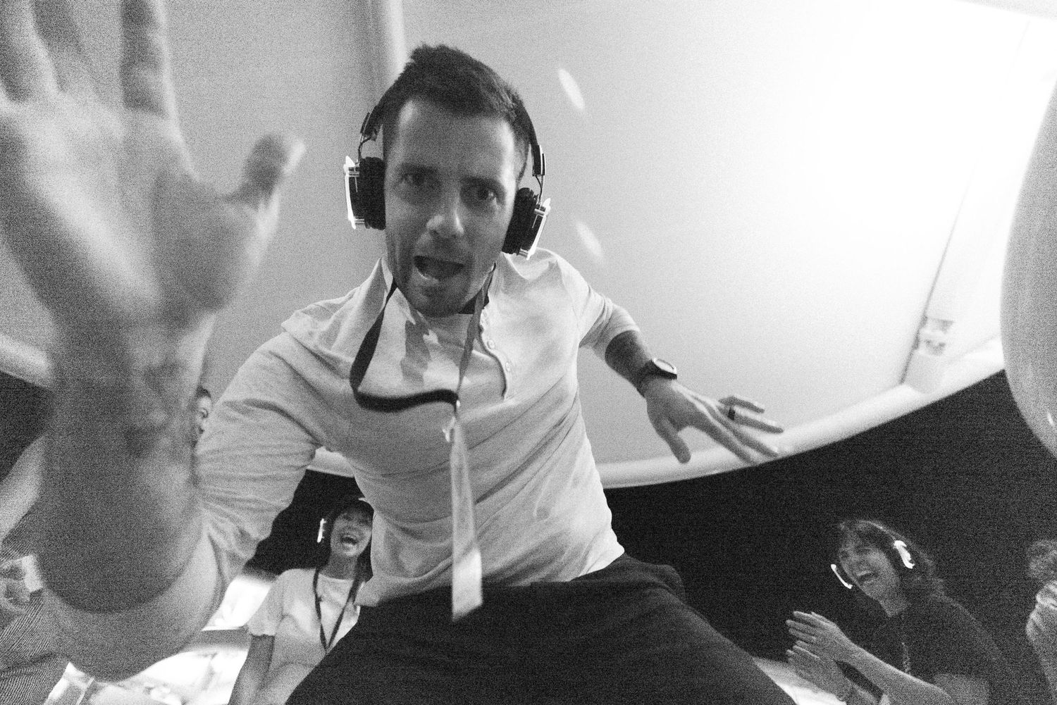 Black and white photo of DJ wearing headphones with raised hand during performance.