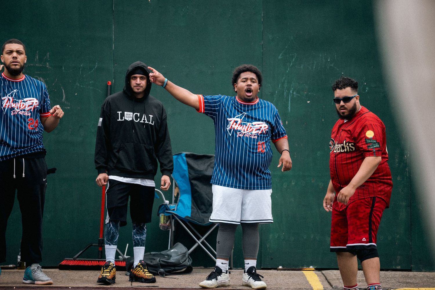 People in sports-themed attire gather against a green wall for a social event or game.