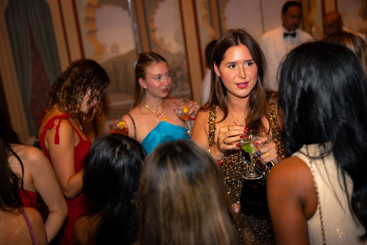 Crowd of party attendees socializing in a dimly lit venue.