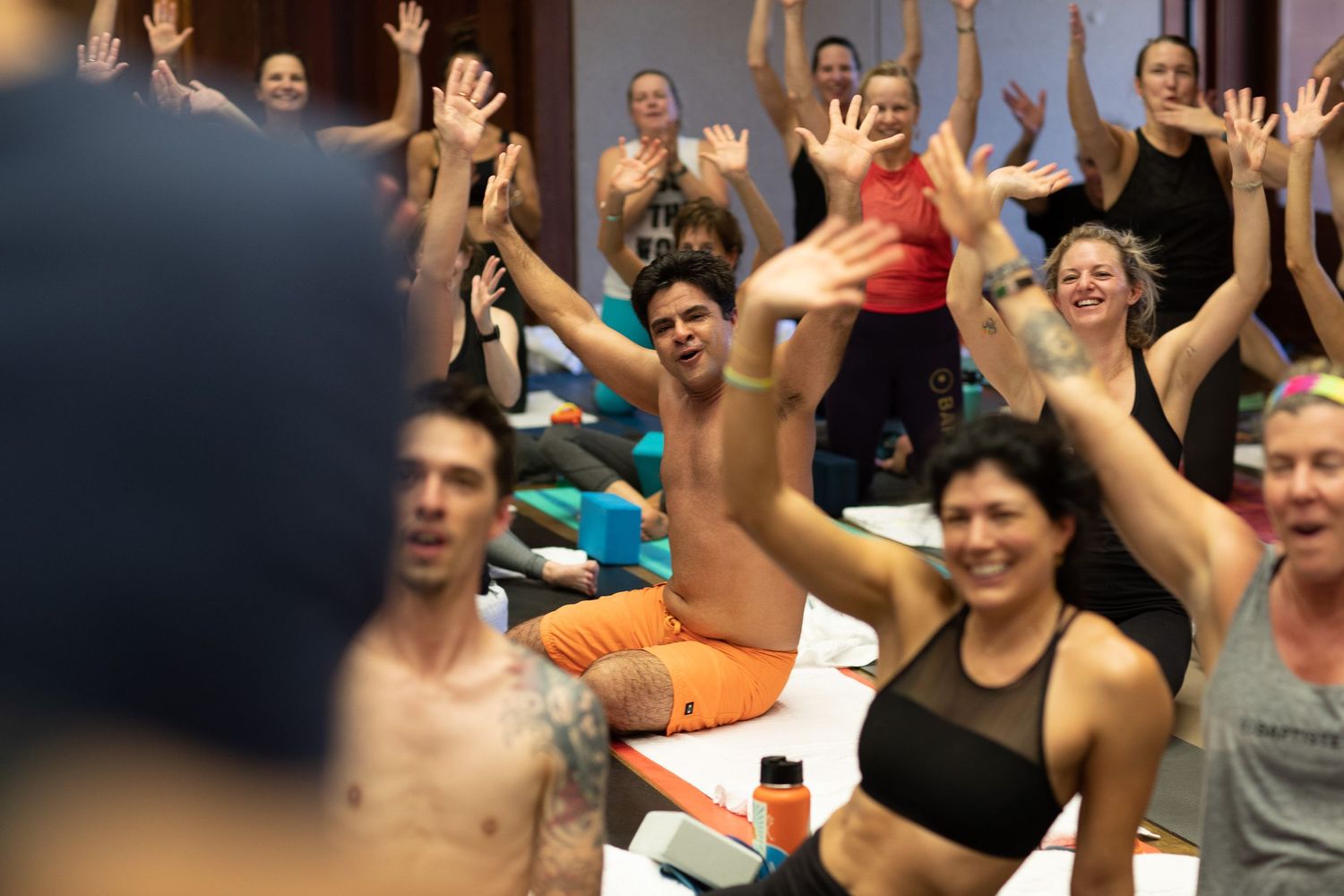 Enthusiastic crowd raises hands in excitement during a high-energy fitness workshop.
