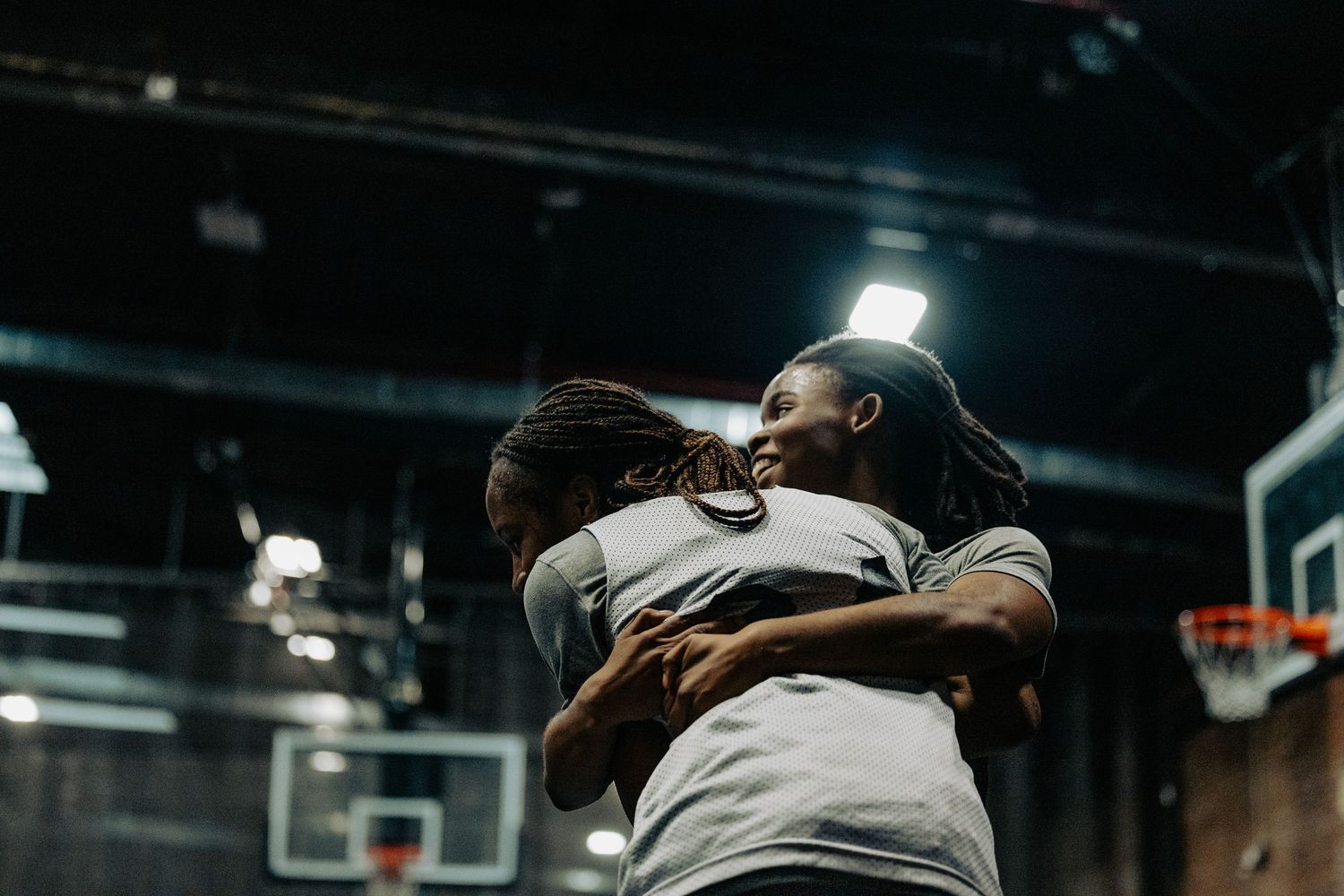Two athletes share an emotional embrace during basketball practice.
