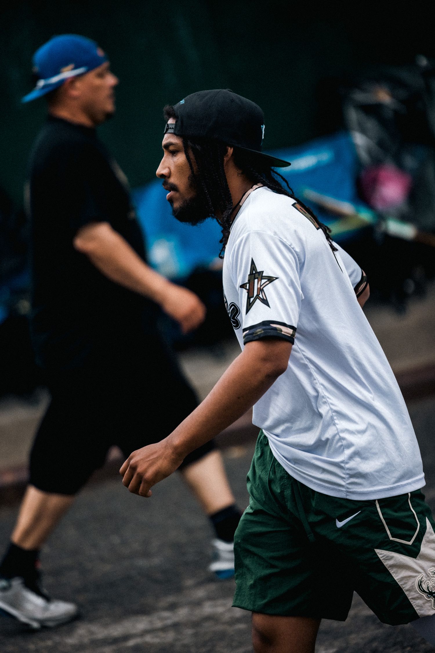 An athlete in white jersey and green shorts running during a sporting event.