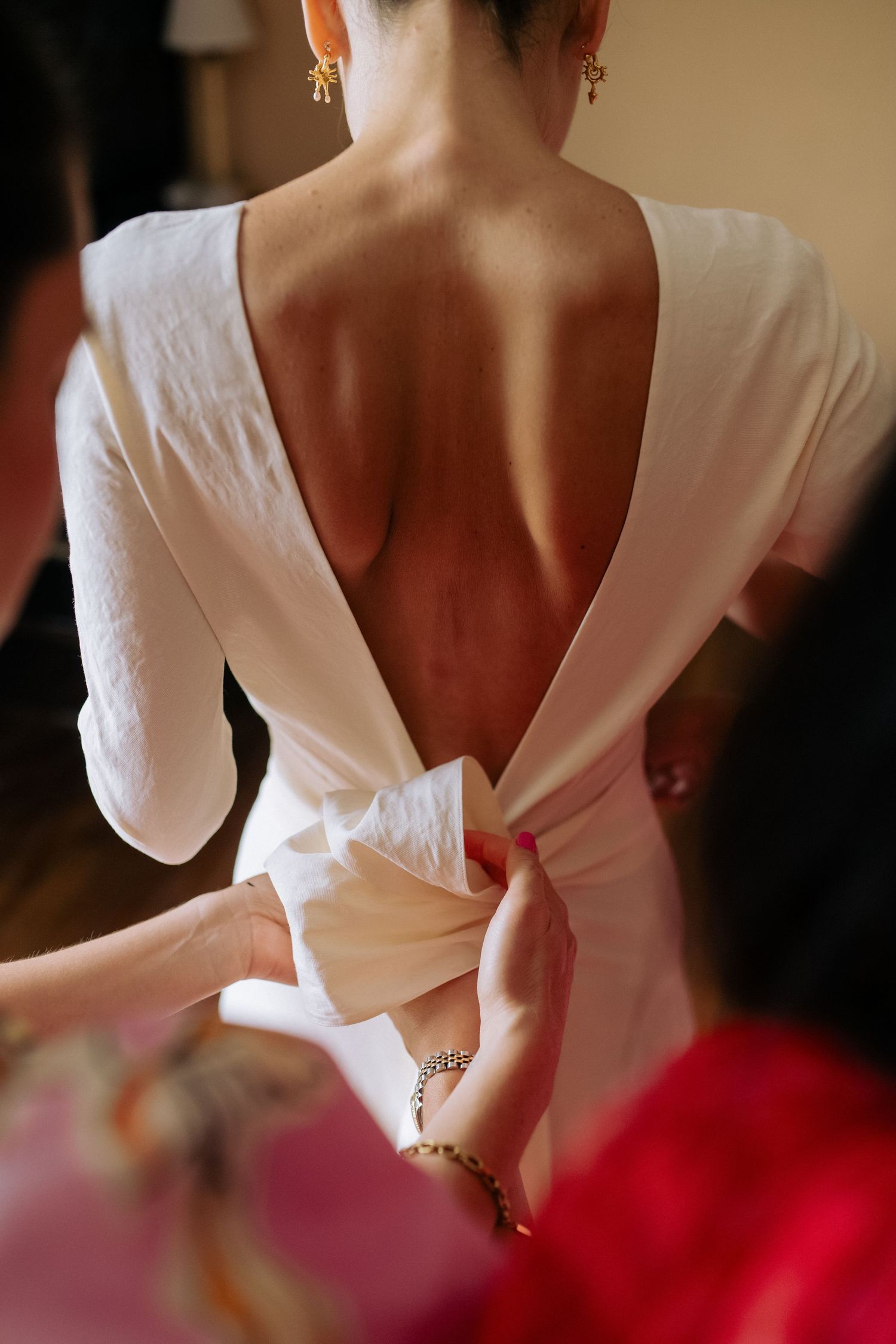 A sequence of close-up shots showing the back details of a bridal dress during preparations.