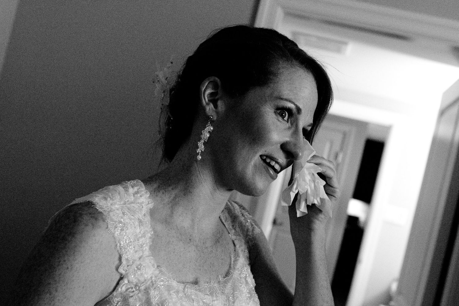 An emotional moment captured in black and white of someone in a wedding dress wiping away tears.