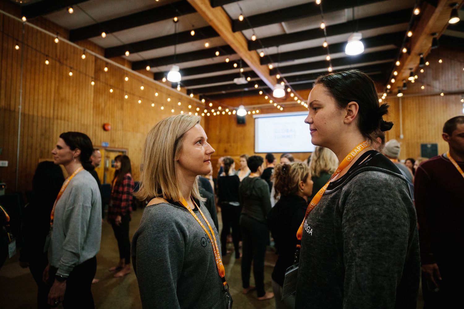 Two people engaged in conversation under string lights at an indoor event.