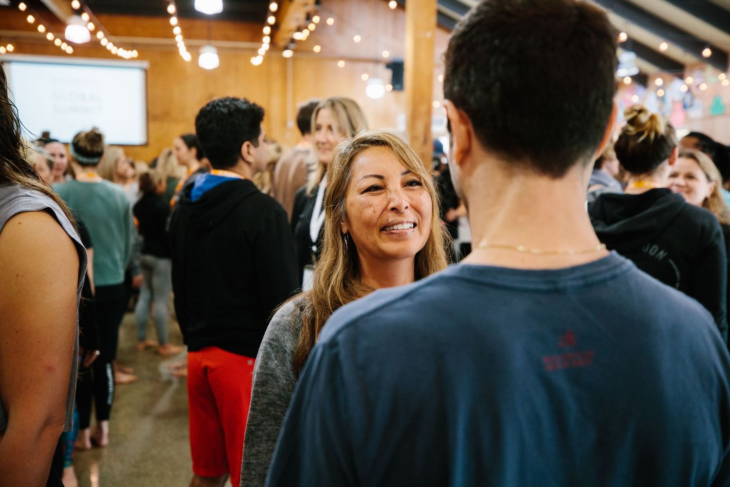 People mingling and socializing at an indoor event with decorative lighting.