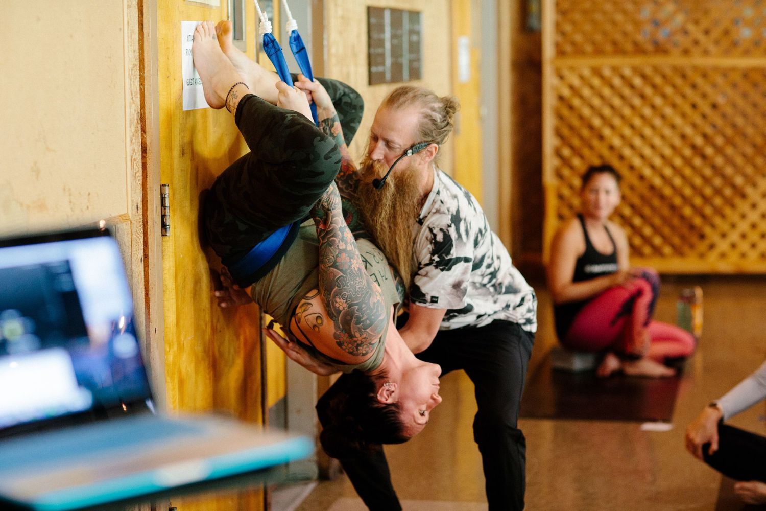 Yoga practitioners performing inversion poses on mats in a studio with lattice wall decor.