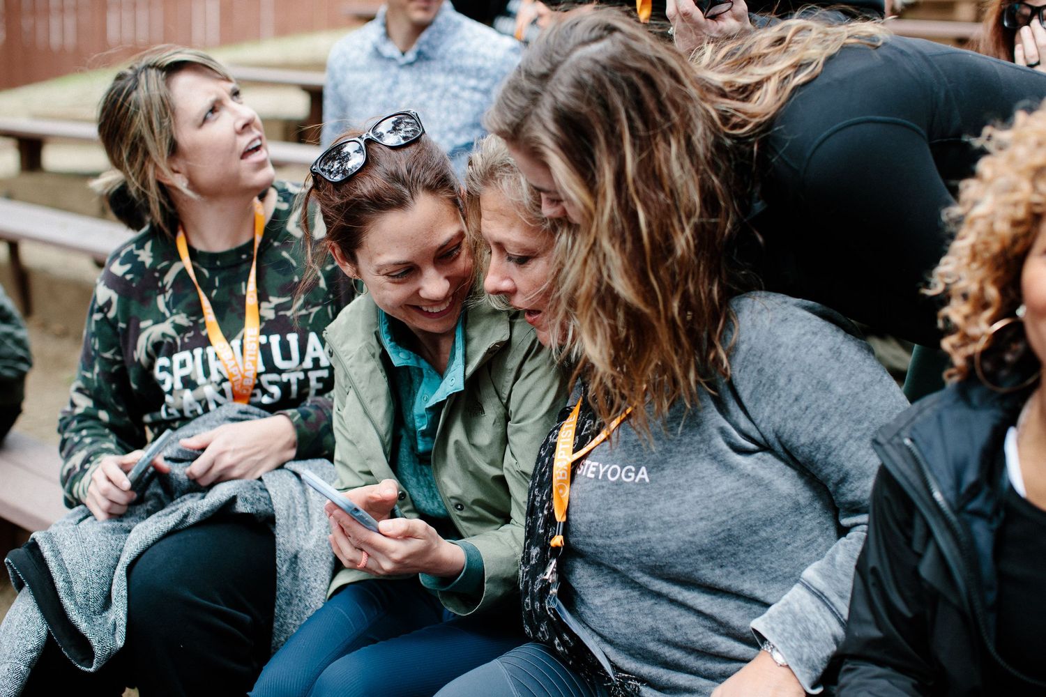 People engaged in animated conversation and laughter at an outdoor social gathering.