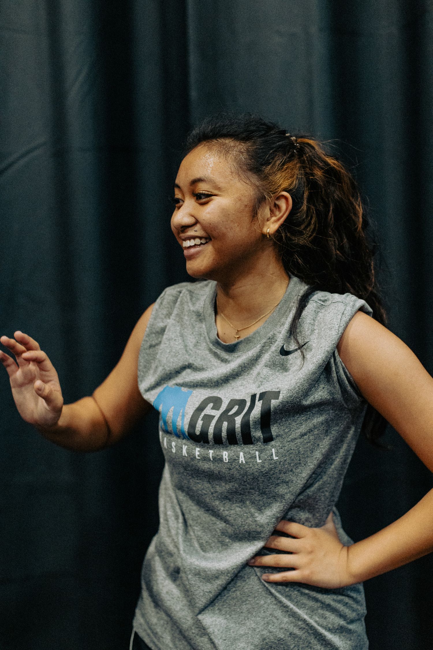 Basketball player in gray GRIT jersey smiling during practice session.