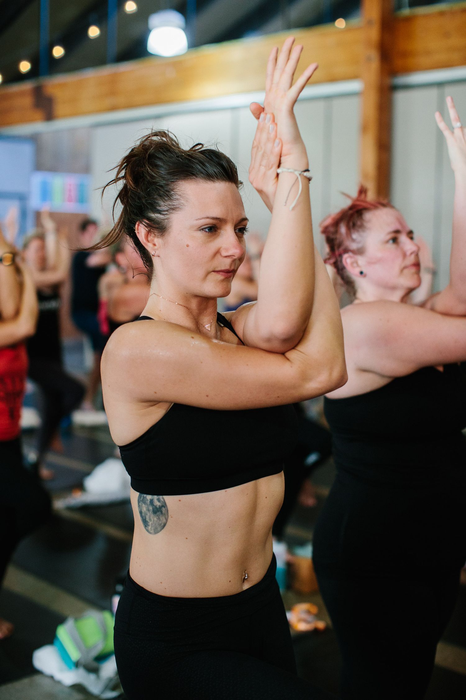 Fitness participants in black athletic wear doing synchronized arm movements during exercise.