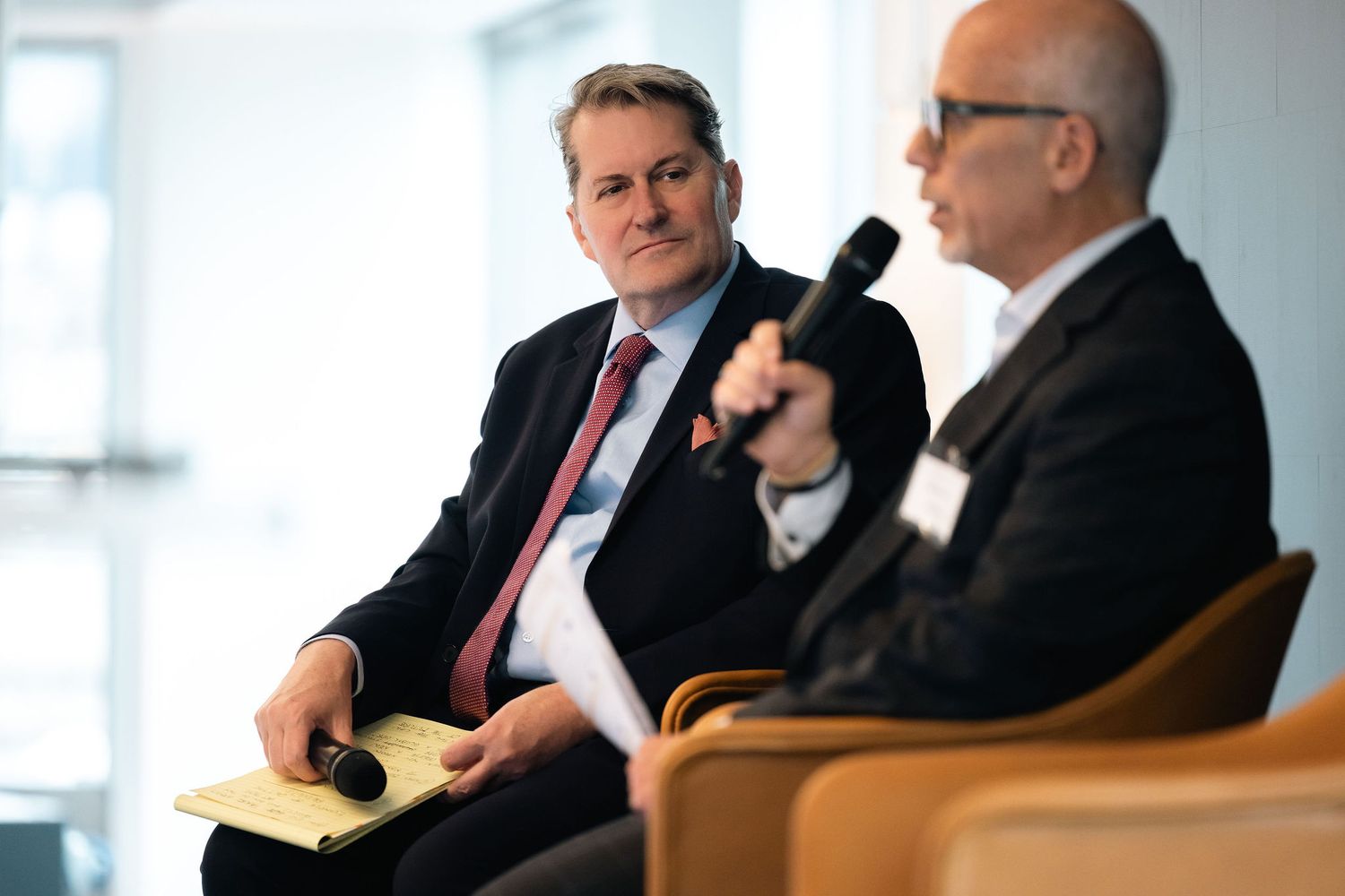 Corporate executives seated in a row during a business panel presentation.