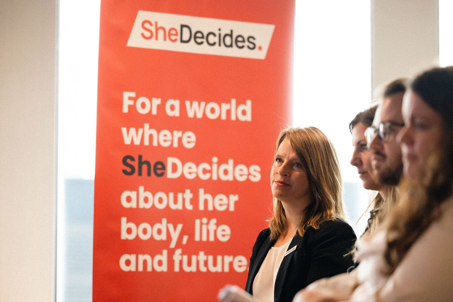 A series of orange and white banners with text about women's empowerment displayed in a conference setting.