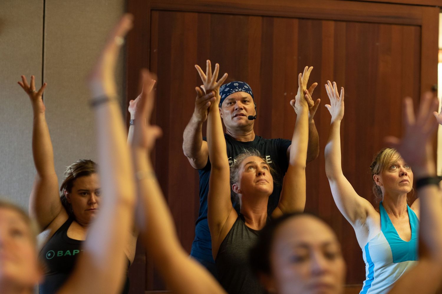 Group with raised arms during a spiritual or wellness gathering in an indoor setting.