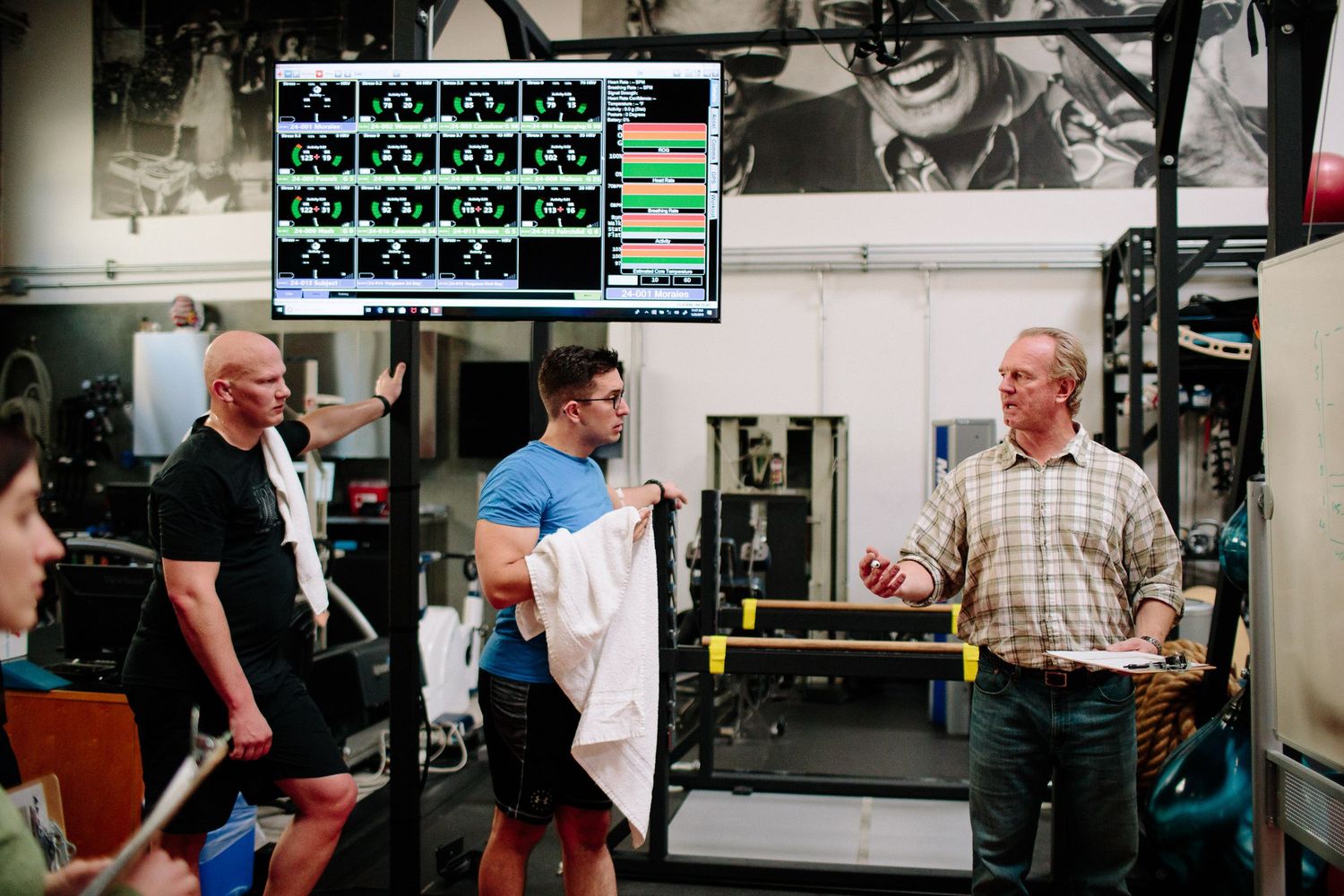 Group discussing near medical equipment with monitors displaying data in background.