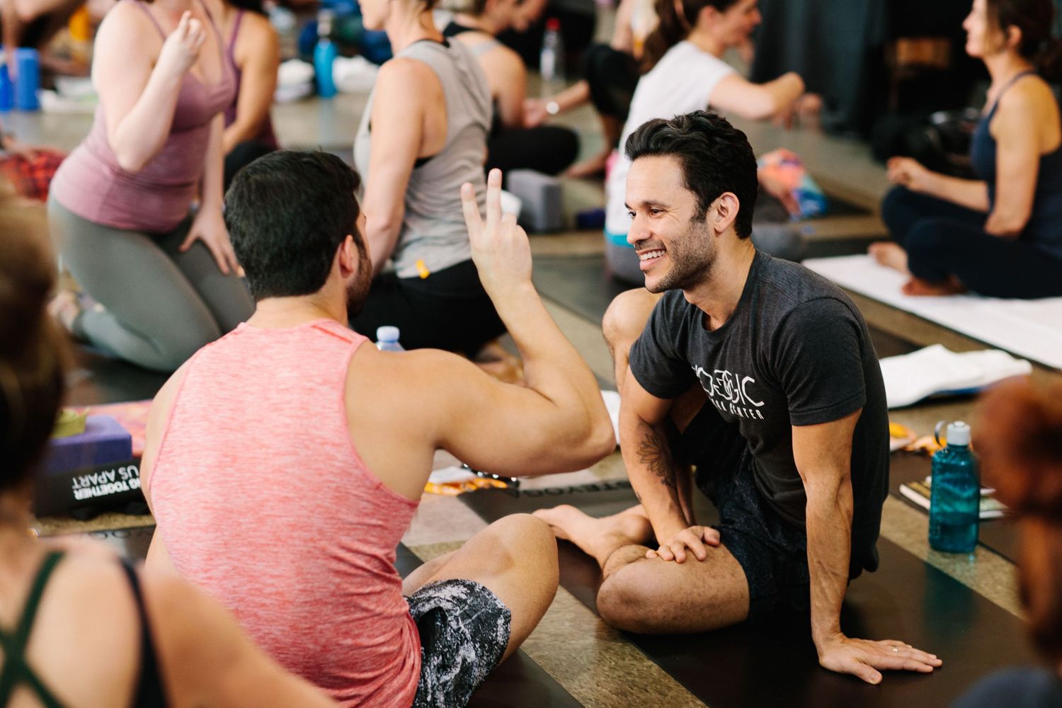 People laughing and socializing during a yoga workshop in a studio setting.