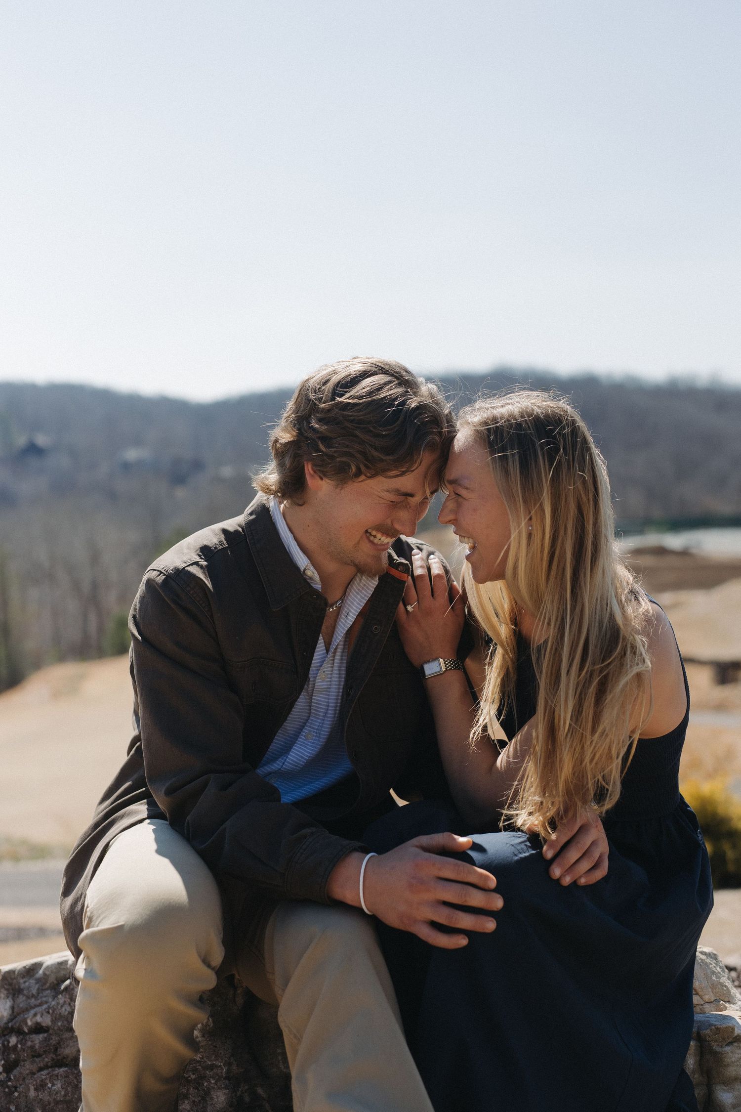 Romantic outdoor proposal scene with a couple embracing against a mountain backdrop.