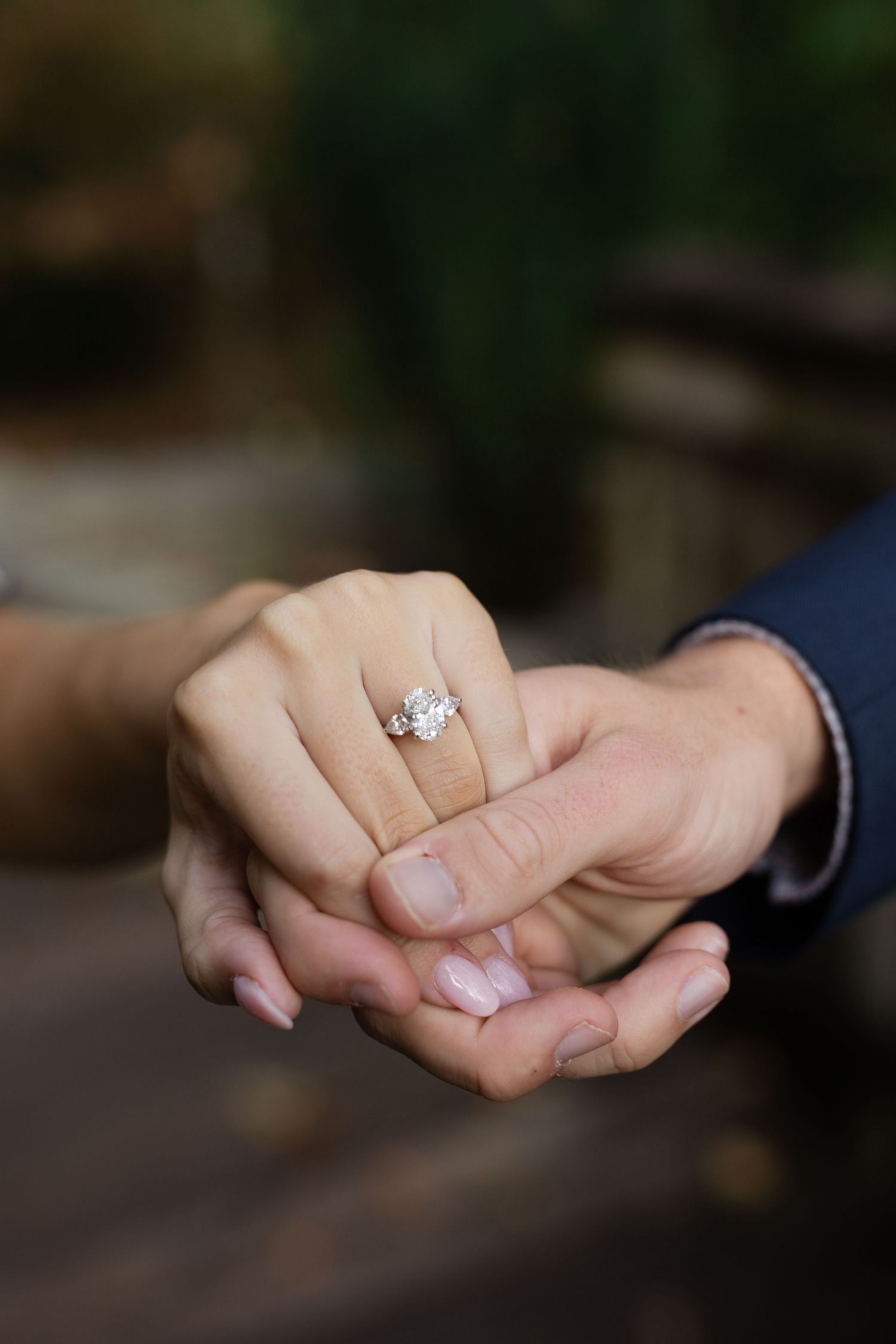 Hands intertwined showing off a sparkling diamond engagement ring.