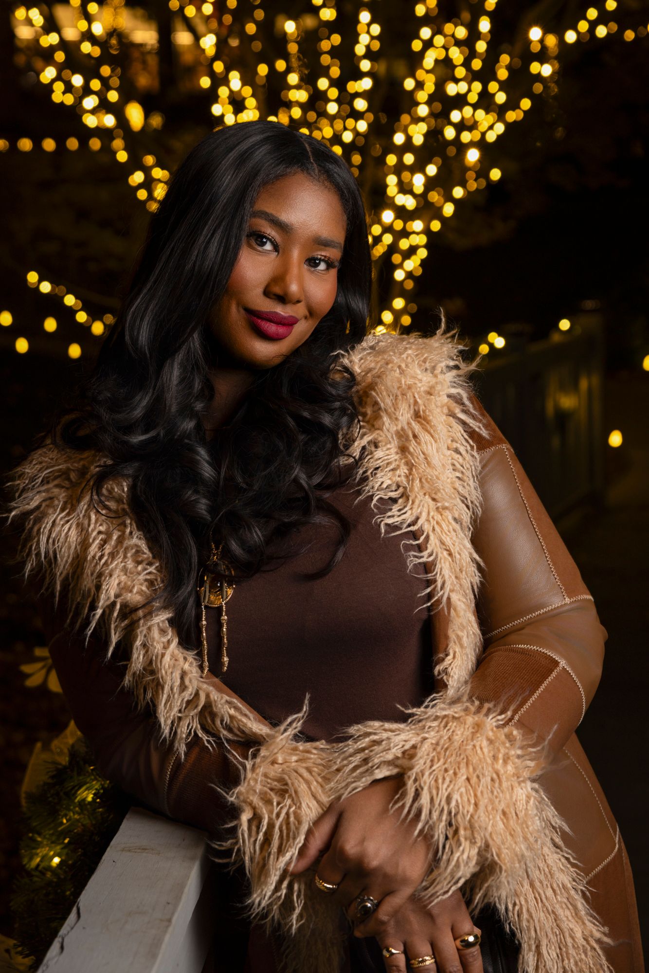 Glamorous portrait with feather boa and sparkling bokeh lights in background.