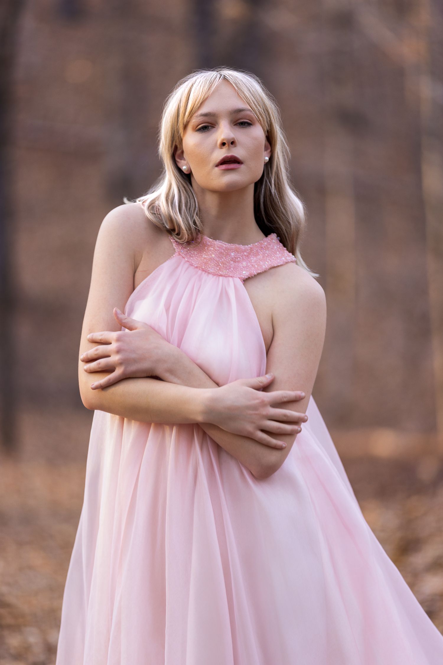 Flowy pink halter dress photographed in an autumn forest setting.