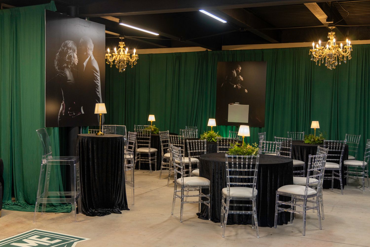 Large event space with green curtains, chandeliers, and formal table settings.