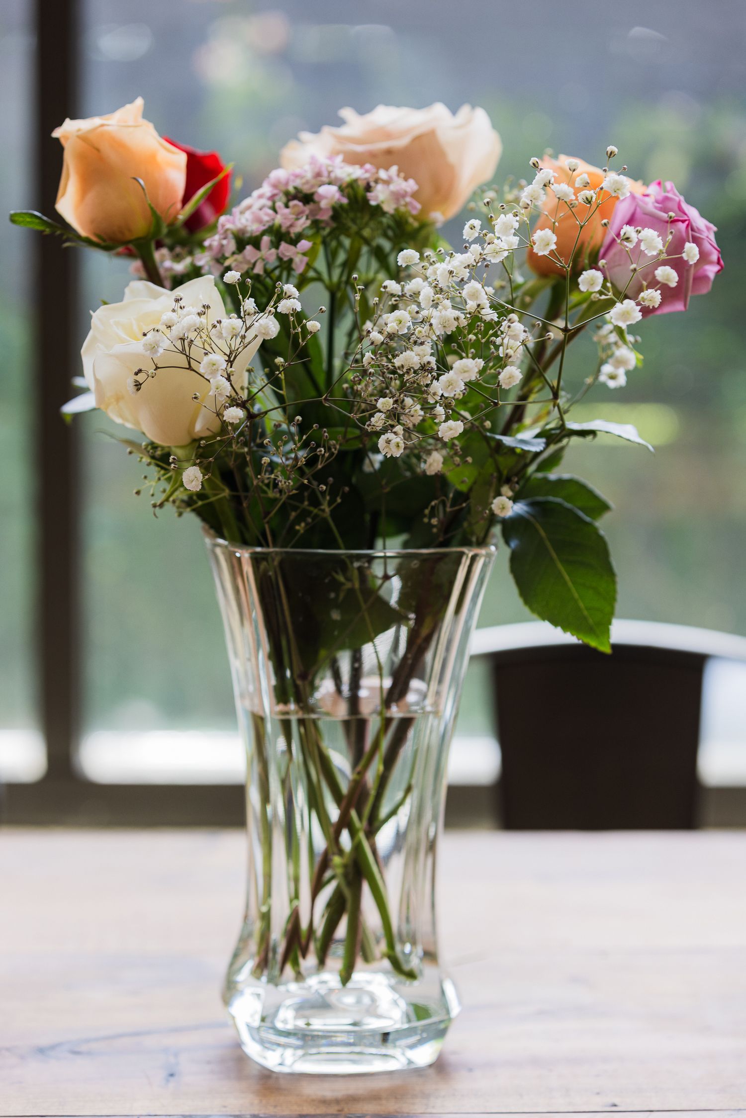 Fresh roses and baby's breath flowers arranged in clear glass vases on display.