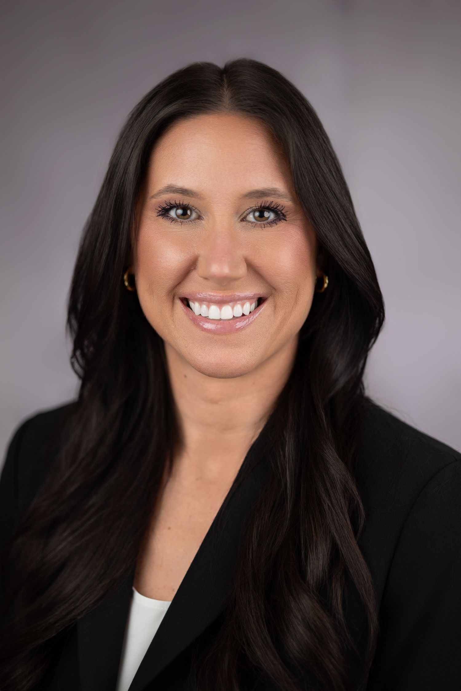 Professional headshot series against a grey background showing different expressions.