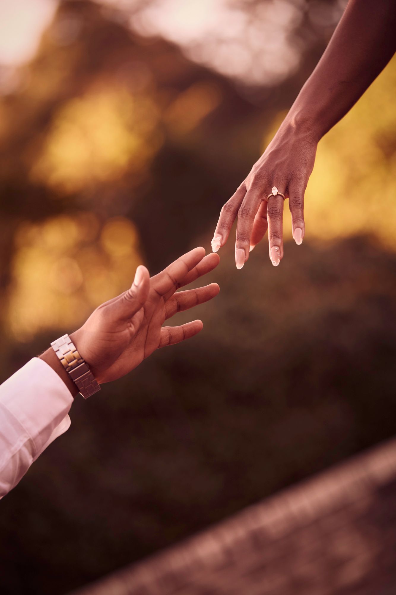 Close-up of hands exchanging a ring during a romantic sunset proposal.