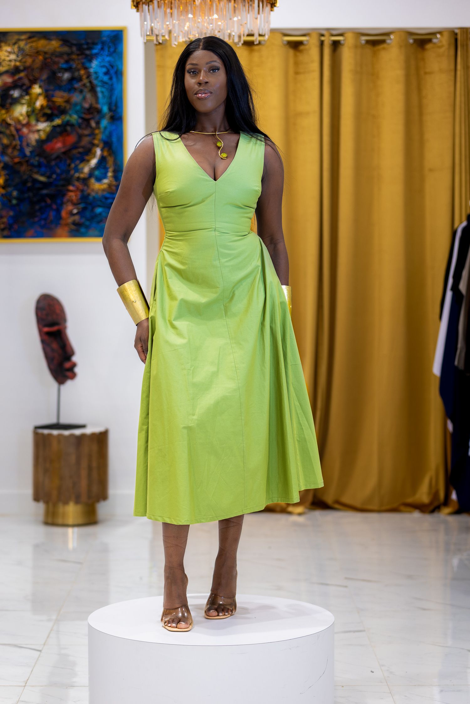 Lime green midi dress showcased in modern gallery setting with gold curtains.