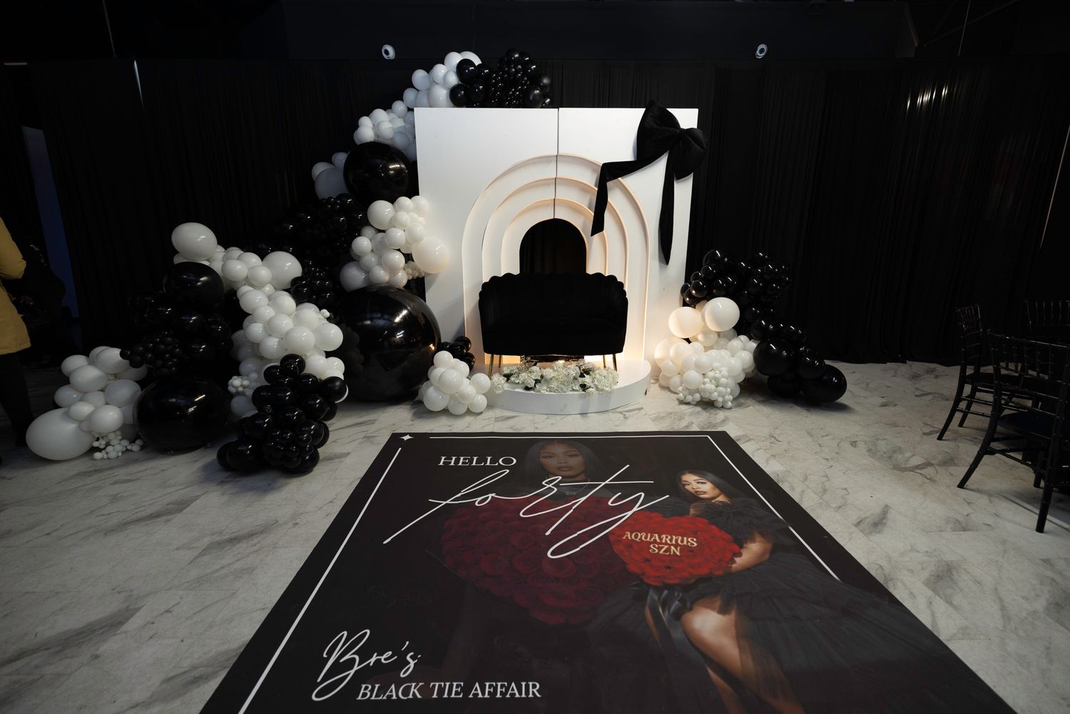 Dark event space with dramatic lighting and cloud-like white balloon installations.
