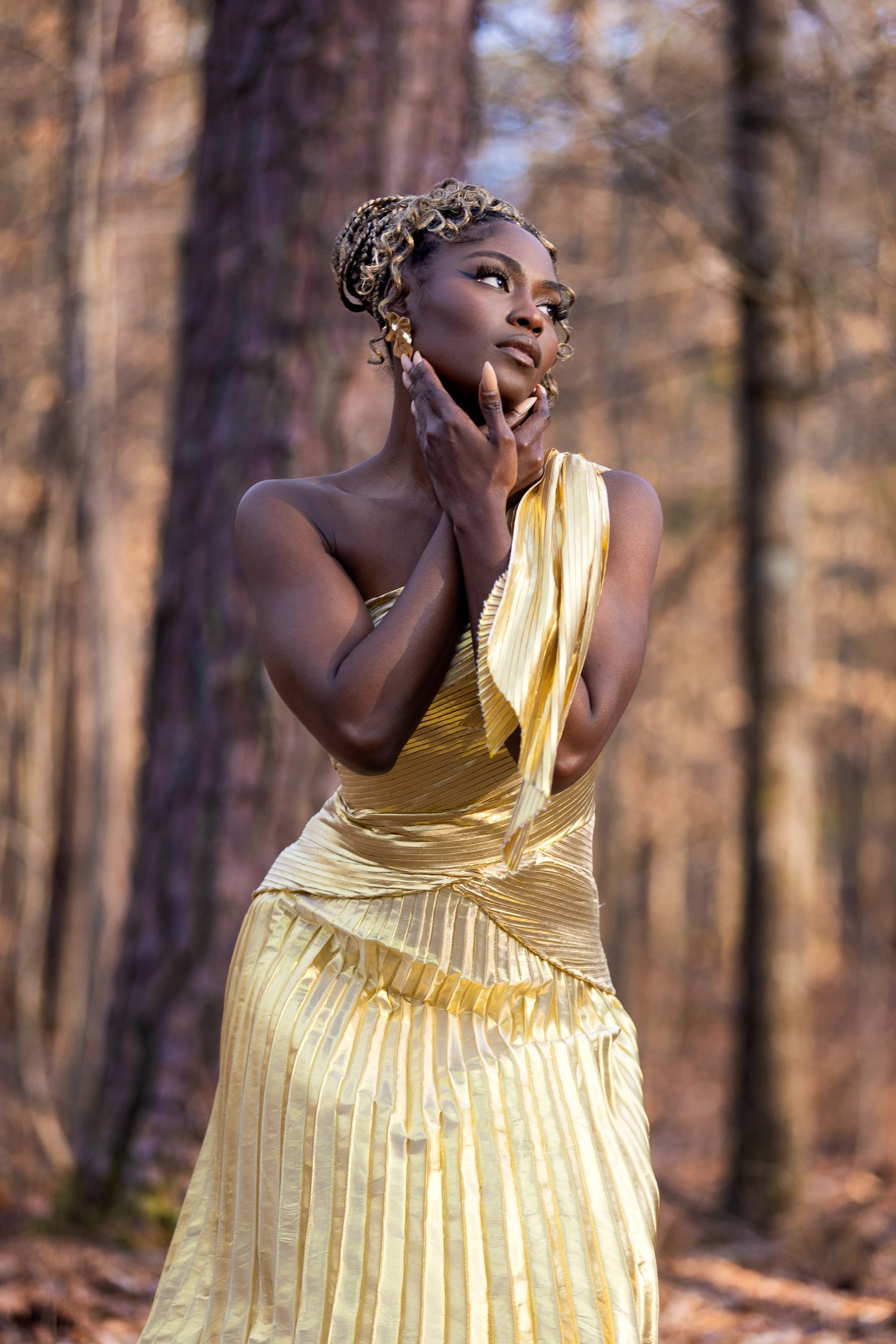 Ethereal outdoor portrait in flowing yellow dress amid sunlit forest.
