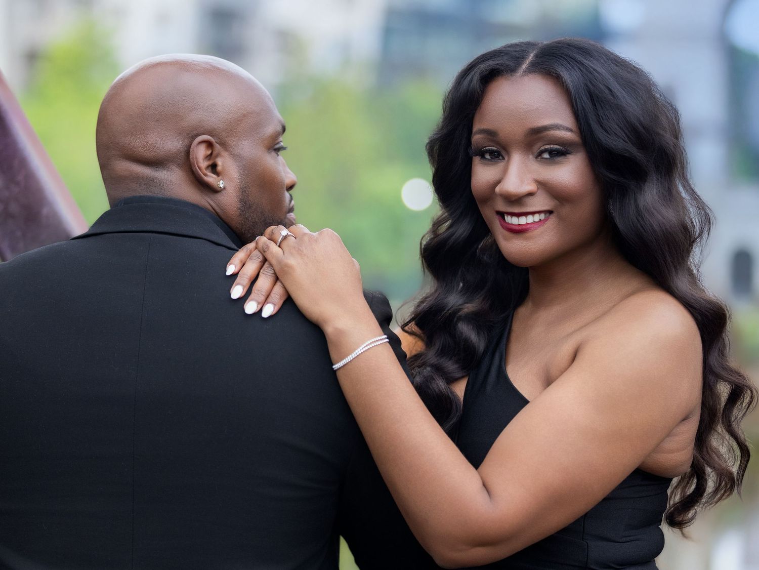 A couple shares a tender moment during their engagement photoshoot while wearing formal black attire.